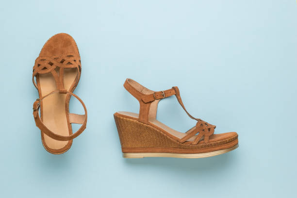 istock Stylish brown women's suede sandals on a blue background. Flat lay. 1323384025