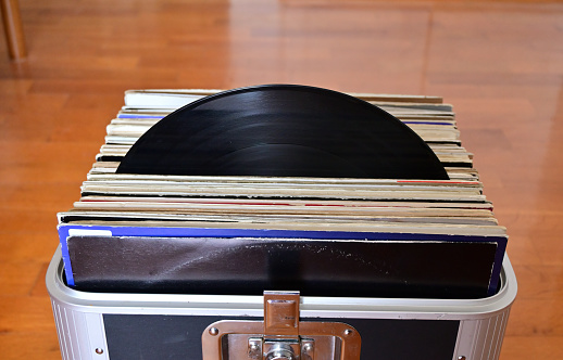 Lot of vinyl record inside a record case with a record protruding from its case .