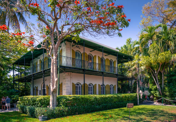 Ernest Hemingway home in Key West. Key West, USA - 04.30.2017: Ernest Hemingway home in Key West. Beautiful, lime-colored villa in Spanish colonial style with tropical garden around it. Porch and wooden window shades. Luxury home. hemingway house stock pictures, royalty-free photos & images