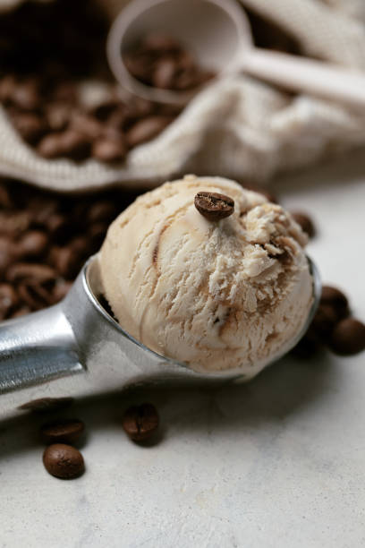 istock Silver scoop with coffee ice cream and coffee beans on white clay background. 1323385401