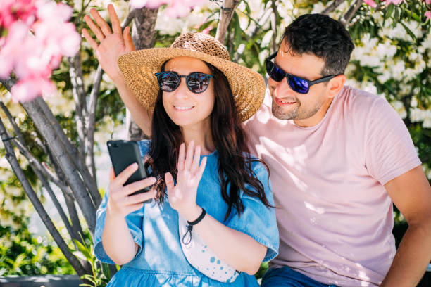 istock Young couple video conferencing with their friends on vacation 1323386087