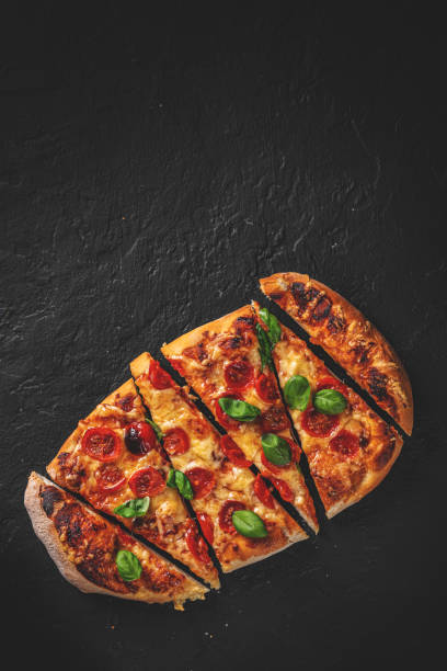 istock flatbread Pizza with Mozzarella cheese, Tomatoes, pepper, Spices and Fresh Basil. Italian pizza. Pizza Margherita or Margarita on Dark grey black slate background 1323386465