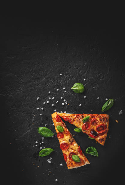 istock wo slice of flatbread Pizza with Mozzarella cheese, Tomatoes, pepper, Spices and Fresh Basil. Italian pizza. Pizza Margherita or Margarita on Dark grey black slate background 1323389280