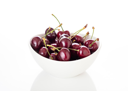 A bowl of cherries on the table with a napkin. The concept is to make breakfast.