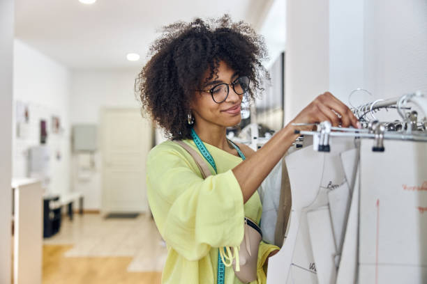 Happy African-American fashion designer takes cardboard basic pattern in sewing workshop