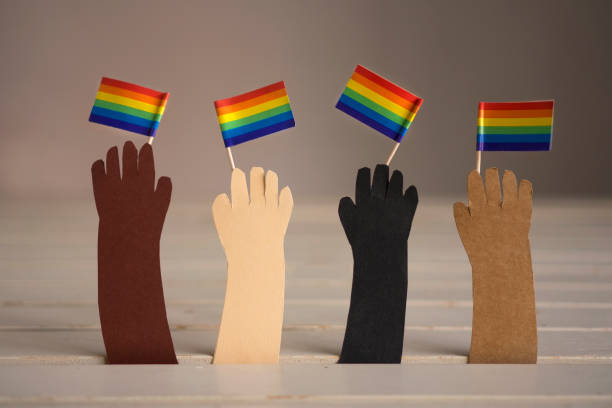 Four multicultural hands made from paper holding rainbow LGBTQIA flags A whitte background with four varied hands holding rainbow flags racial equality photos stock pictures, royalty-free photos & images