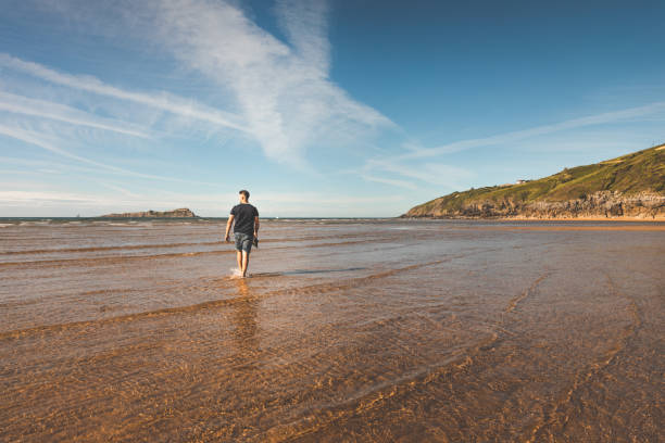 istock Young caucasian man walking at the beach 1323399421