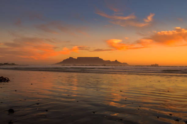 istock Dramatic sky at sunset beach in Bloubergstrand cape town with table mountain at back drop 1323402315