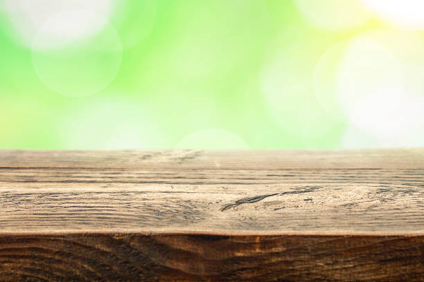 istock Empty wooden table with defocused foliage and sun highlights, oval and round light spots in the background. Mock-up for design with copy space. 1323409268