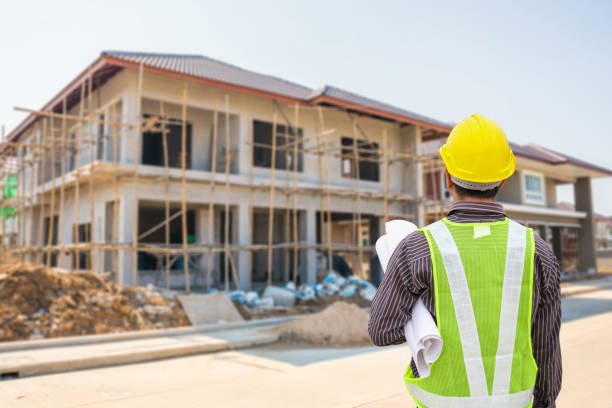 istock young professional engineer in protective helmet and blueprints paper at the house building construction site 1323410192