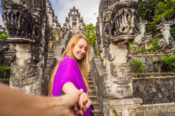 follow me photo. Young woman tourist on background of Three stone ladders in beautiful Pura Lempuyang Luhur temple. Summer landscape with stairs to temple. Paduraksa portals marking entrance to middle sanctum jaba tengah of Pura Penataran Agung, Bali. sígueme foto. mujer joven turista en el fondo de tres escaleras de piedra en el hermoso templo pura lempuyang luhur. paisaje de verano con escaleras al templo. portales de paduraksa que marcan la entrada al sanctum medio jaba tengah de pura penataran agun