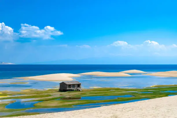 Chalet on the sand island of Qinghai Lake, Qinghai Province, China . Desert and endless clear blue lake