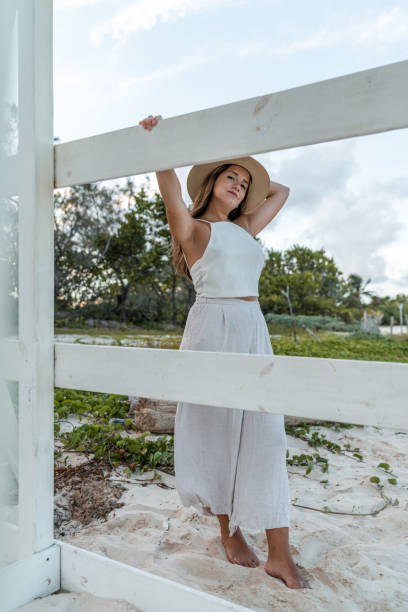 istock young woman with hat posing on a white wooden structure on the beach 1323421015