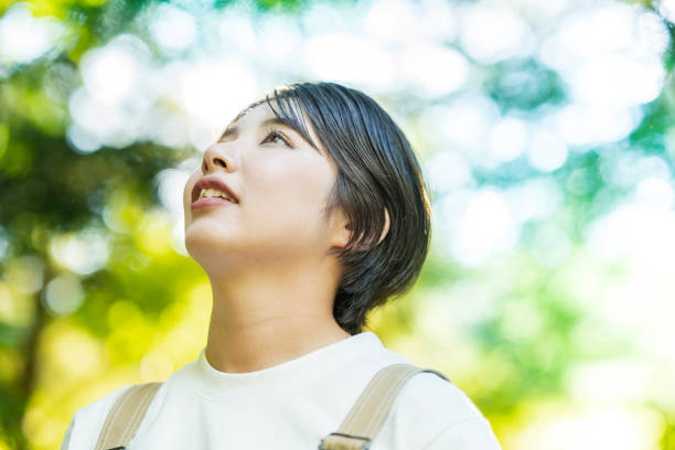 istock Woman looking up at the trees in the forest 1323425636