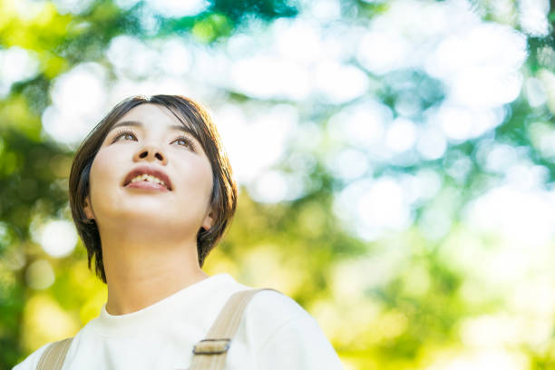 istock Woman looking up at the trees in the forest 1323425667