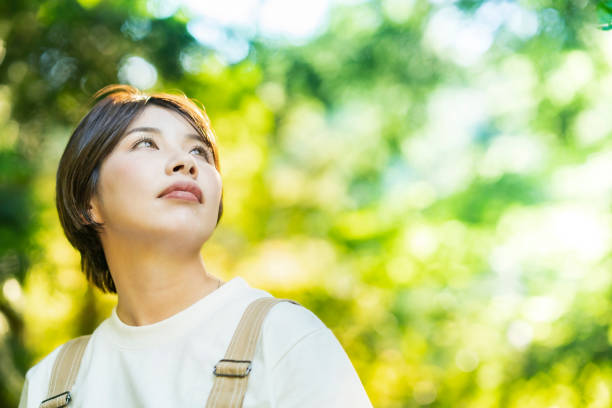 istock Woman looking up at the trees in the forest 1323425679