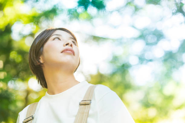 istock Woman looking up at the trees in the forest 1323425743