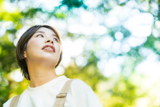 istock Woman looking up at the trees in the forest 1323425768