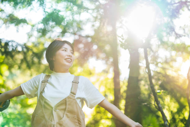 istock Woman looking up at the trees in the forest 1323426324
