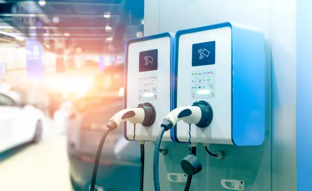 Photo of Electric car charging station for charge EV battery. Plug for vehicle with electric engine. EV charger station. Clean energy. Charging point for EV car. Green power. Future transport technology.
