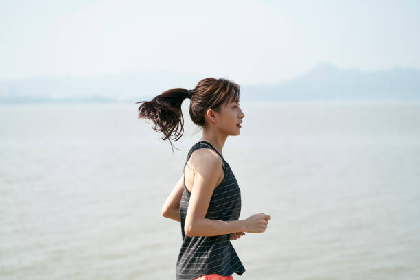 istock young asian woman running on beach 1323432114