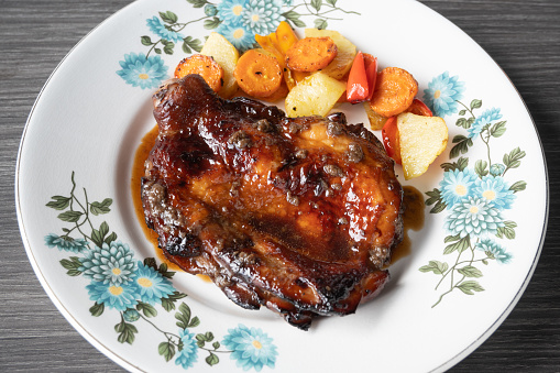 A plate of juicy succulent roast chicken with potatoes, carrots and peppers.