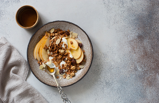 Muesli, apples, pears and yogurt in rustic plate. Healthy breakfast concept. Flat lay. Copy space