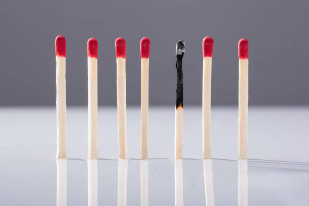 Burnt Matchstick Separated By Red Matchsticks Against Grey Background