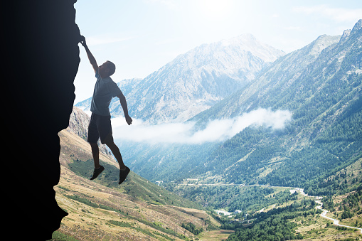 Businessman jumping off the mountain looking rain of money on the other side, risky job pursue wealth concept