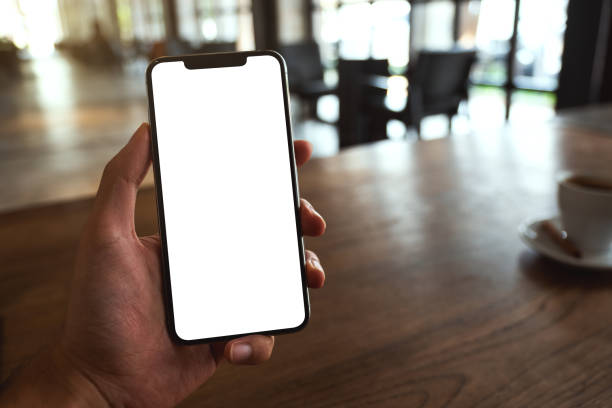 istock a man holding black mobile phone with blank white screen in cafe 1323438072