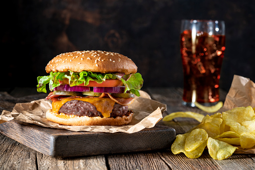 Cheeseburger Burger Patty classic with potato chips and cola soda menu on rustic wooden table background