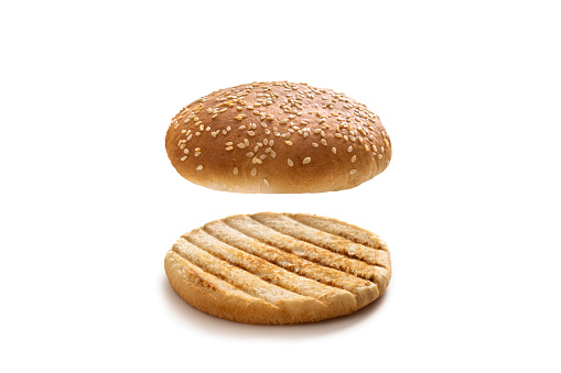 Burger bun bread with sesame seeds half cut open and grilled isolated on white background