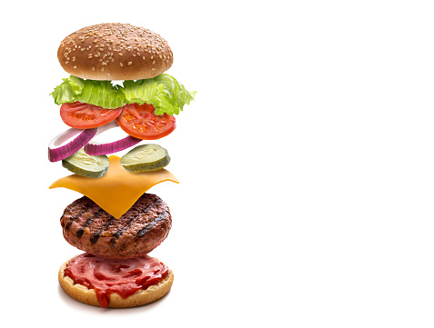 Burger layered ingredients as explosion flying open bun cheeseburger isolated on white background