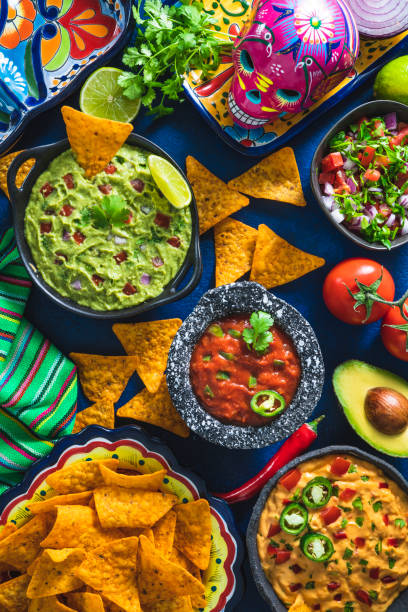 istock Mexican dip sauces guacamole, cheedar dip, tomato salsa and pico de gallo with Nacho chips 1323443833
