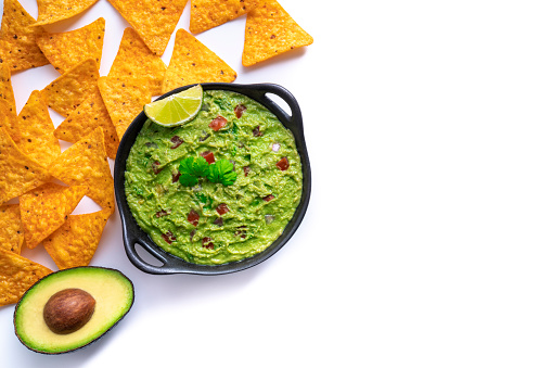 Guacamole avocado Dip with Nacho chips with tomato and chili isolated on white background