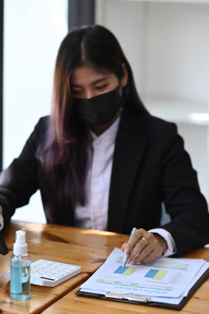 istock Businesswoman in protective mask analyzing business data at office. 1323444439