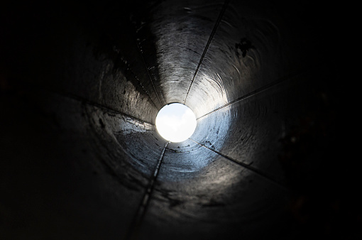 Abstract black tunnel made with round pipe. Concept of exit or endless. A light in the end of a tunnel.