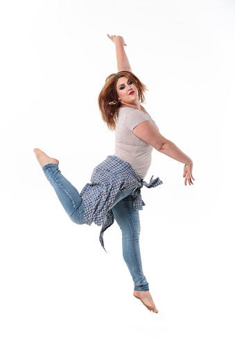 Young woman mid-air in jump as a casual dancer. Jeans and white blouse on a white background.