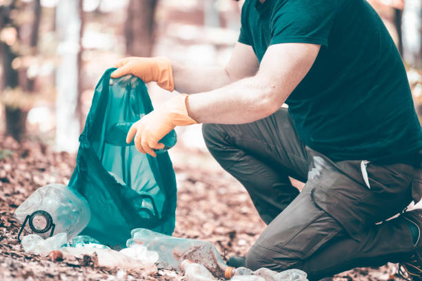 istock Volunteer collecting garbage in the woods. 1323447830