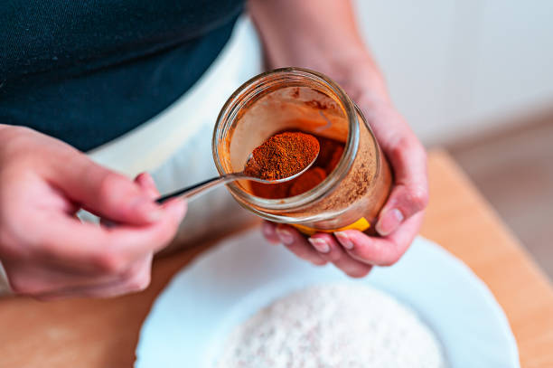 A Woman is Mixing a Cayenne Pepper and Flour to Prepare a Meal. Close-Up Photo of Female Chef Preparing Ingredients for Cooking by Mixing a Red Pepper and Flour in a Plate. cayenne powder stock pictures, royalty-free photos & images