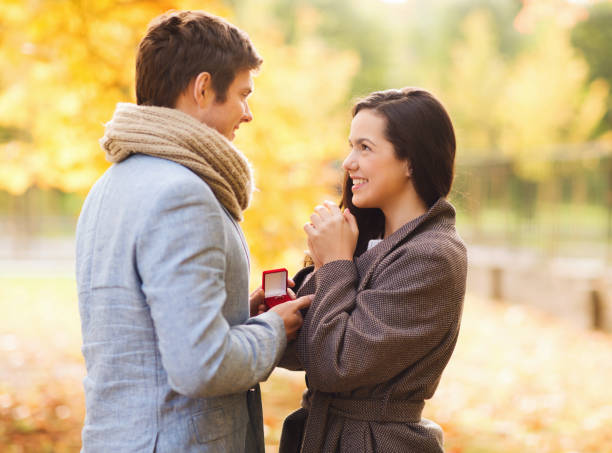 istock smiling couple with red gift box in autumn park 1323452416