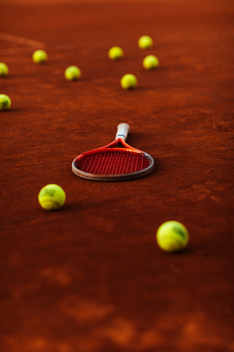 Clay tennis court with multiple tennis balls lying around