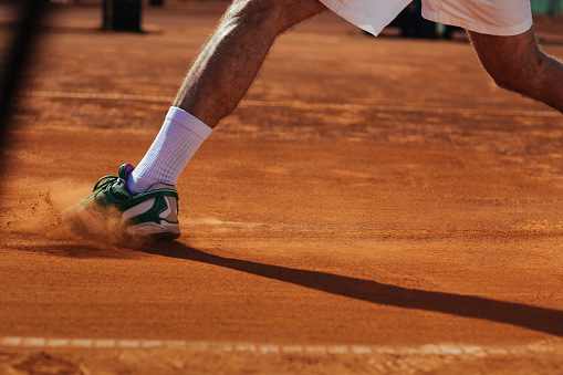 An unrecognisable tennis players leg sliding on a clay court
