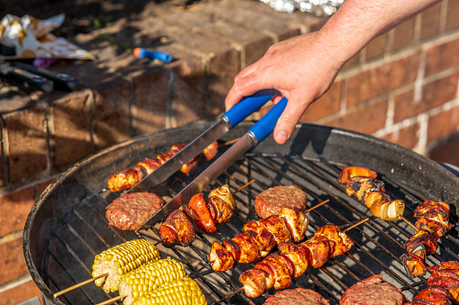 Hot dog burgers, chicken kebabs and corn cooking on the BBQ