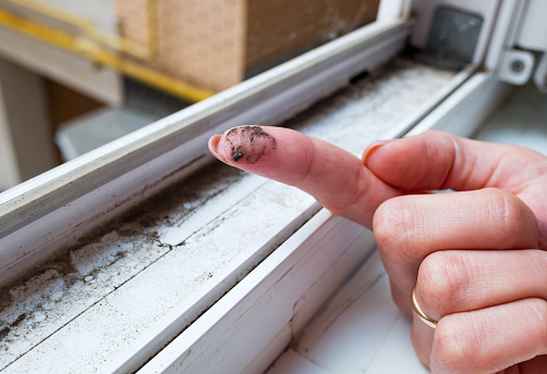 A dirty finger with dirt showing the need for cleaning the house, washing PVC window frames. Cleaning concept.