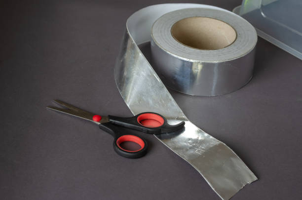 istock Scissors, aluminum tape, and a clear plastic container on a gray background. 1323456499