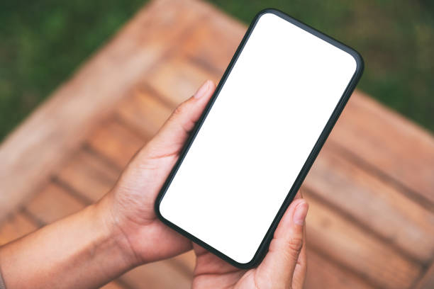 istock Top view mockup image of hands holding black mobile phone with blank white screen 1323456729