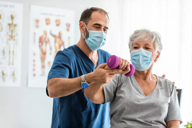 une infirmière de soins d’âge mûr aide un patient âgé à faire des exercices de physiothérapie - centre de désintoxication photos et images de collection