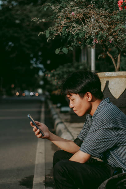 istock Teenager waiting using his smartphone 1323461742