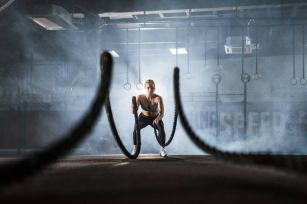 istock Female athlete exercising with battle ropes in a gym. 1323462089